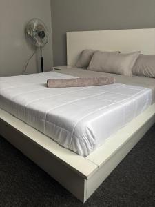 Cama blanca grande en habitación con ventilador en Bukoto Ntinda Luxury Apartments, en Kampala