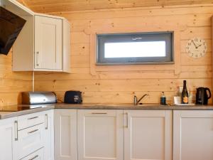 a kitchen with white cabinets and a television on the wall at Oak Lodge - Uk30005 in Lindal in Furness +13 photos