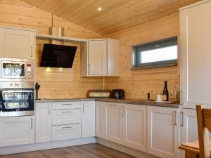 a kitchen with wooden walls and white cabinets and a window at Oak Lodge - Uk30005 in Lindal in Furness