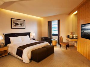 a hotel room with a bed and a large window at Resorts World Genting - Genting Grand in Genting Highlands