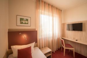 
a hotel room with a television and a bed at Hotel Leander in Bitburg
