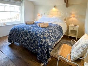 a bedroom with a blue and white bed and a window at Cobble Cottage in Instow