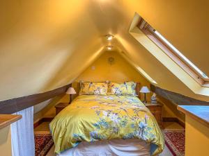 a bedroom with a bed in the attic at Yelt Cottage in Wootton