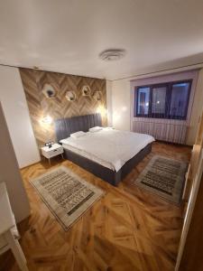1 dormitorio con cama, suelo de madera y ventana en KUZINATRA Apartament, en Slănic-Moldova