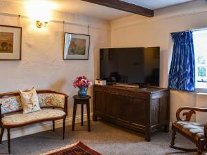 sala de estar con TV grande y 2 sillas en Needle House, en Ravenstonedale