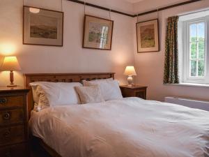 Un dormitorio con una gran cama blanca con dos lámparas. en Needle House, en Ravenstonedale
