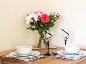 een tafel met een vaas met bloemen en twee glazen bij Keepers Retreat, The Annex in Roughton +6 foto's