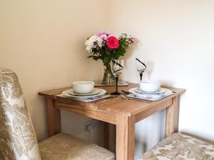 een tafel met twee kopjes en een vaas met bloemen bij Keepers Retreat, The Annex in Roughton