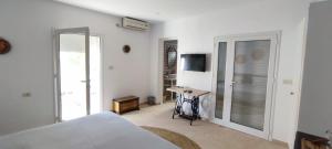 a bedroom with a bed and a desk with a television at Chambre Suite Paco avec accès piscine in Midoun
