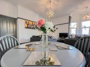 a dining room with a table with a vase of flowers at Salty Towers in Saltburn-by-the-Sea +18 photos