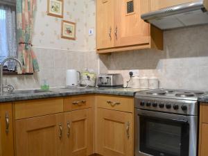 a kitchen with wooden cabinets and a stove top oven at Printers Cottage in Ambleside