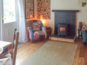 a living room with a chair and a wood stove at Druimbhan, 1 Railway Cottage, in Lochailort