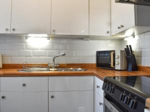 a kitchen with white cabinets and a sink and a microwave at Blue Sands in Morecambe