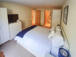 a bedroom with a large white bed and a television at Apartment 4, Zinc in Newquay