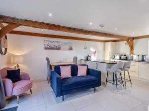 a living room with a blue couch and a kitchen at The Annexe At Park Farm Barns - Uk39379 in Snettisham