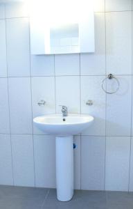 a white bathroom with a sink and a mirror at Prasonisi Club in Kattavía