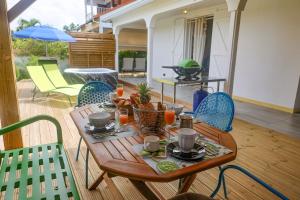 un tavolo e sedie di legno su un patio di Cottage de la Plage - Le Gosier, proche plage, jacuzzi, location Prestige Caraïbes a Le Gosier