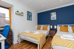 two beds in a room with a blue wall at Open Mind Property - Cozy 2 Bed Room & Free Parking in Portsmouth