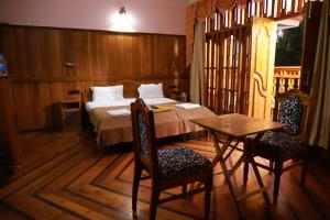 a bedroom with a bed and a table and chairs at Thriphala Ayurveda Yogashram in Trivandrum