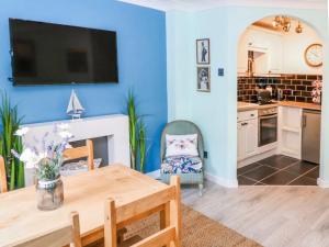 a living room with a table and a tv on the wall at Whitby Sands in Whitby