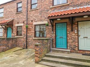a brick house with blue doors and stairs at Whitby Sands in Whitby