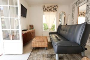 un soggiorno con divano in pelle nera e specchio di Cottage de la Plage - Le Gosier, proche plage, jacuzzi, location Prestige Caraïbes a Le Gosier