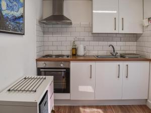 a kitchen with white cabinets and a stove at Seren Cottage By The Sea in Bodorgan