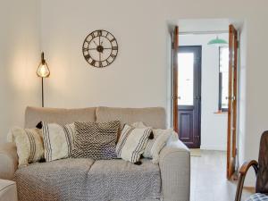 a living room with a couch and a clock on the wall at Black Spout Cottage in Moulin