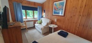 a room with a bed and a chair and a window at Meads Cabin in Charmouth