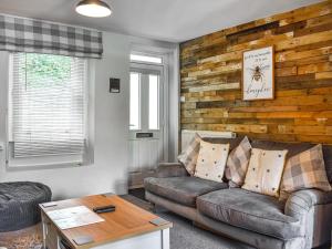 a living room with a couch and a wooden wall at Beeswax Cottage in Dalton in Furness