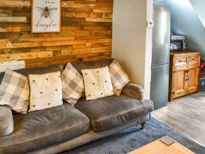 a brown leather couch in a kitchen with a refrigerator at Beeswax Cottage in Dalton in Furness