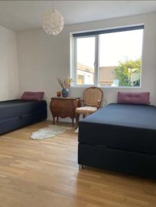 a bedroom with two beds and a table and a window at Cozy villa apartment close to everything in Hørning