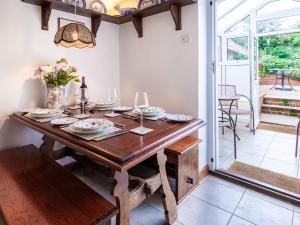 a dining room with a wooden table with plates and wine glasses at Colbridge Cottage in Docking