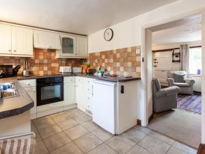 a kitchen with white cabinets and an open door at Colbridge Cottage in Docking