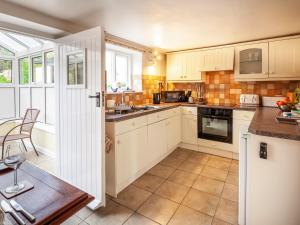 a kitchen with white cabinets and an open door at Colbridge Cottage in Docking +12 photos