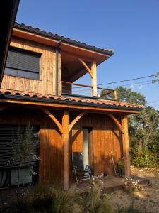 VillevieilleにあるVilla en boisのバルコニーと椅子のある木造住宅