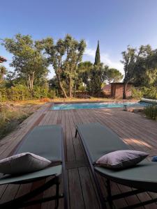 VillevieilleにあるVilla en boisのスイミングプールの隣にあるウッドデッキのラウンジチェア2脚