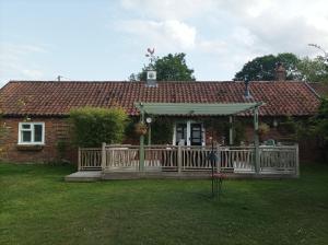 a wooden deck in front of a house at Olde Farm Holiday Cottages in Banham
