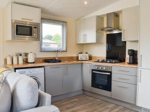 Una cocina con gabinetes blancos y un horno de estufa. en Sunshine Retreat, en Sewerby