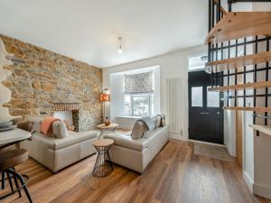 a living room with two couches and a brick wall at Sandy View - Uk43056 in Saundersfoot