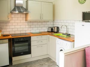 a kitchen with white cabinets and a stove top oven at Willows Barn in Clenchwarton