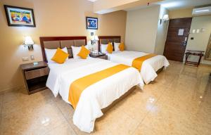 a hotel room with two beds with orange and white sheets at Gran Recreo Hotel - Trujillo - Perú in Trujillo