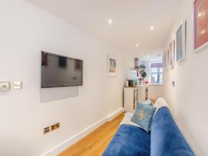a living room with a blue couch and a tv on a wall at Town Square Apartment - Uk45611 in Alnwick