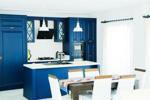 Una cocina con gabinetes azules y una mesa y sillas. en Villa Dalyan Emirhan, en Ortaca