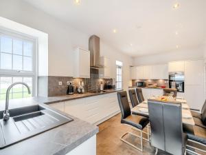 a kitchen with white cabinets and a table with chairs at Kerrytonlia Cottage in Mountstuart