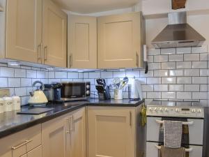 a kitchen with wooden cabinets and a stove top oven at Cartwheel Cottage in Hawes +7 photos