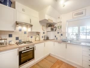 een keuken met witte kasten en een kookplaat oven bij Stonehanger 2 - Cottage in Salcombe +16 foto's