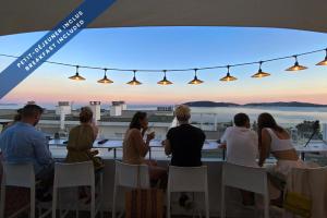 a group of people sitting at a table watching the sunset at Hôtel Les Voiles in Toulon