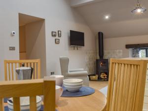 sala de estar con mesa y estufa de leña en The Old Shippon At New Ringstones Farm, en Mellor