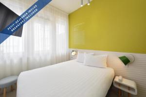 a bedroom with a white bed and a yellow wall at Hôtel Les Voiles in Toulon